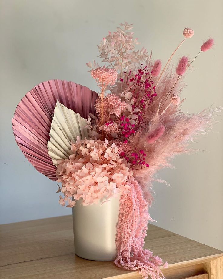 a vase filled with pink flowers on top of a wooden table