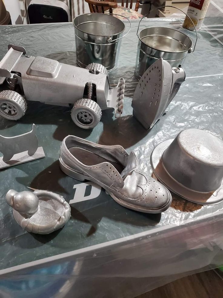 various metal objects are sitting on a table with plastic wrapper and buckets next to them