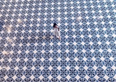 a person standing in front of a blue and white tile floor with circles on it