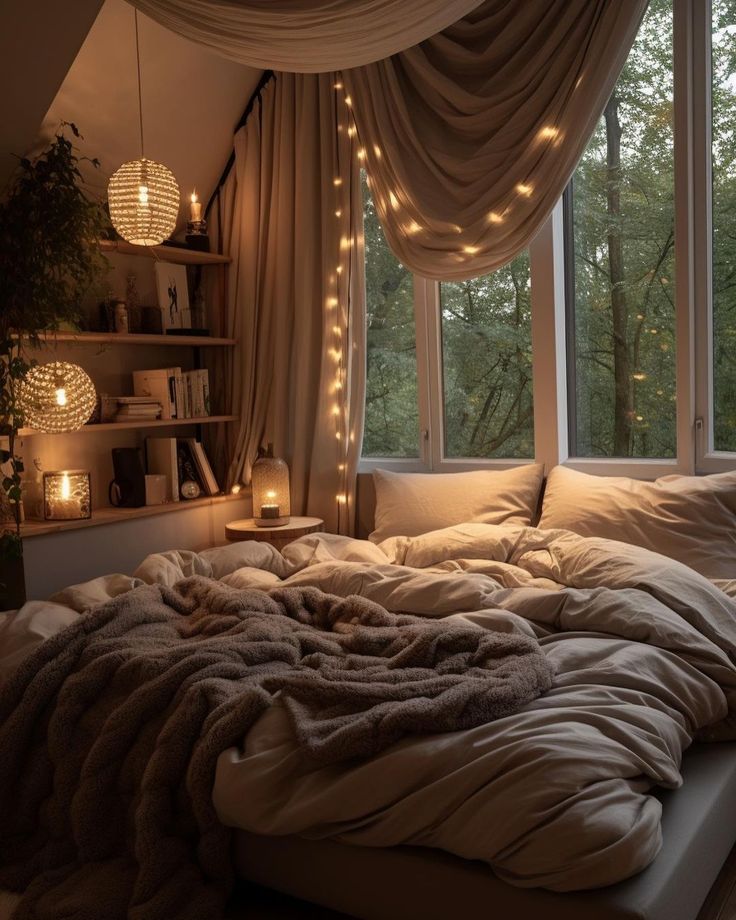 an unmade bed in front of a window with lights strung from the windowsill