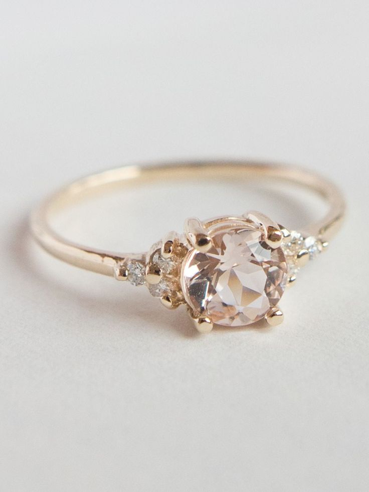 an engagement ring with two stones on the side and one stone in the middle, sitting on a white surface