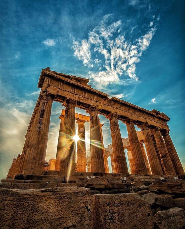 the sun shines brightly through the clouds behind an ancient temple