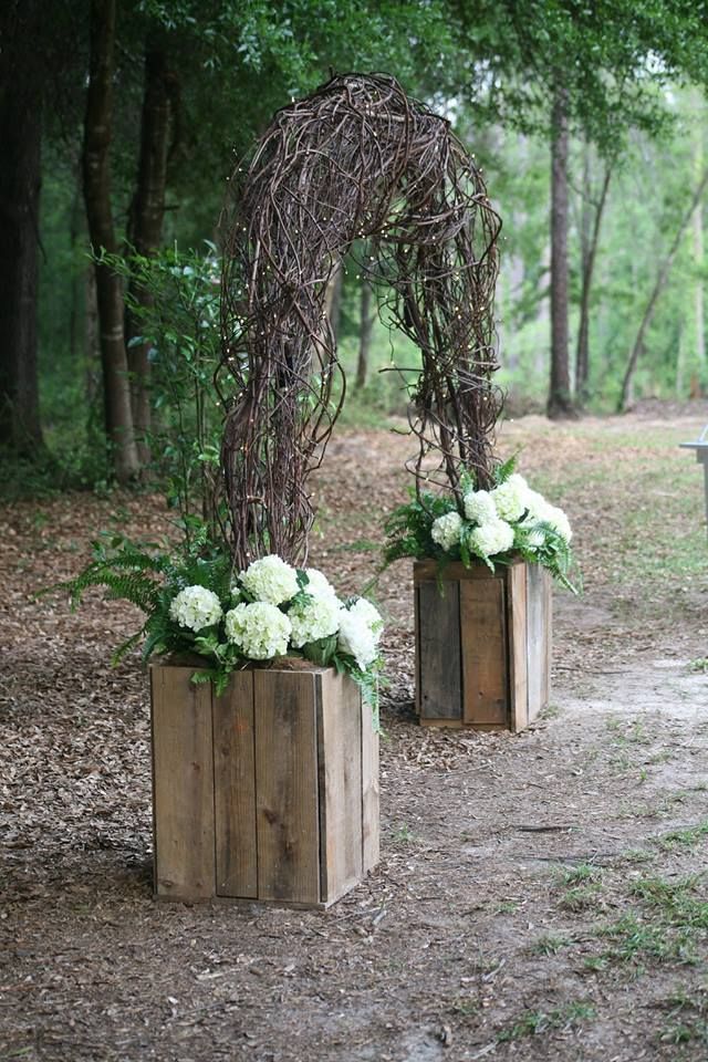 two wooden planters with white flowers in them sitting on the ground next to a bench