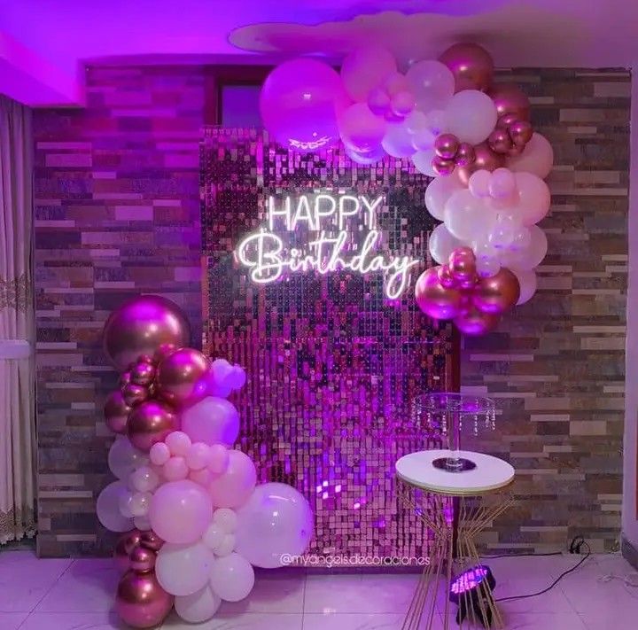 balloons and streamers in front of a happy birthday sign at a party with purple lights