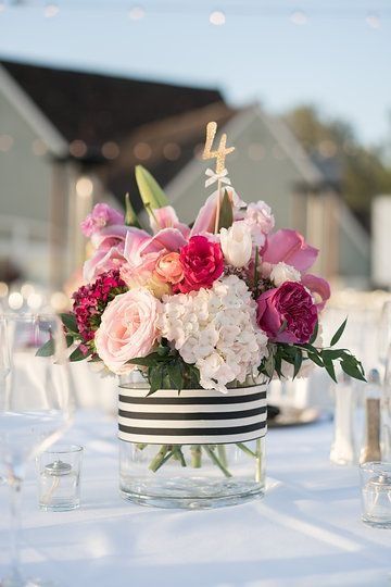 a vase filled with lots of flowers on top of a white tablecloth covered table