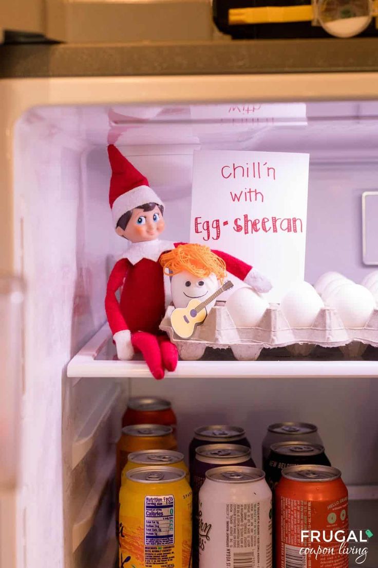 an elf is sitting in the fridge with eggs and yogurt on it, next to a sign that says chillin with egg - sheltan