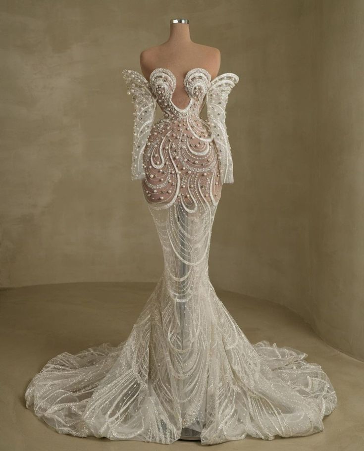 the back of a white wedding dress with an intricate lace pattern on it and long sleeves