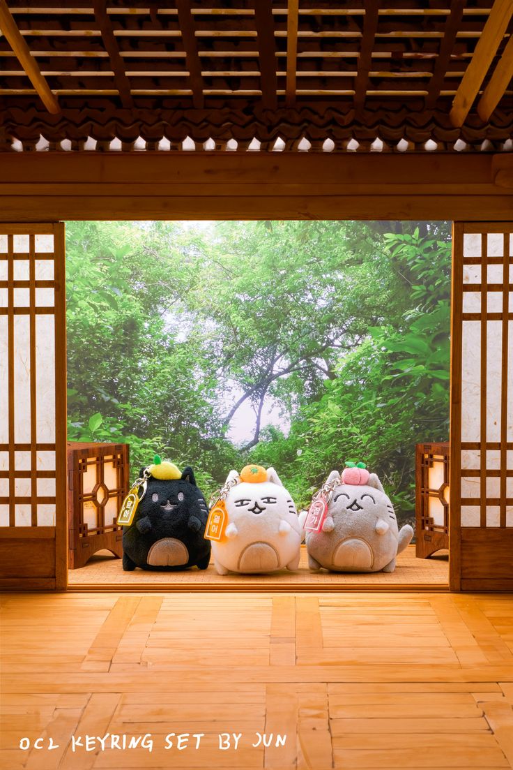 three stuffed animals sitting on top of a wooden floor in front of an open doorway