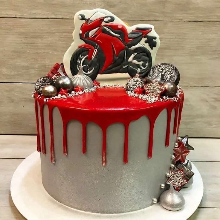 a red and white motorcycle cake on a plate with silver ornaments around the edge,