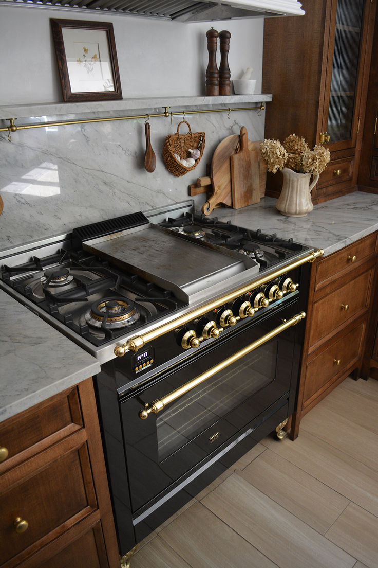 a stove top oven sitting inside of a kitchen next to wooden cabinets and counter tops