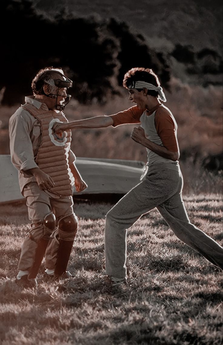 two people are playing frisbee on the grass in front of a car and an airplane