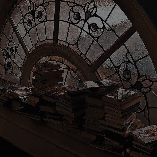 a bunch of books sitting on top of a table next to a stained glass window