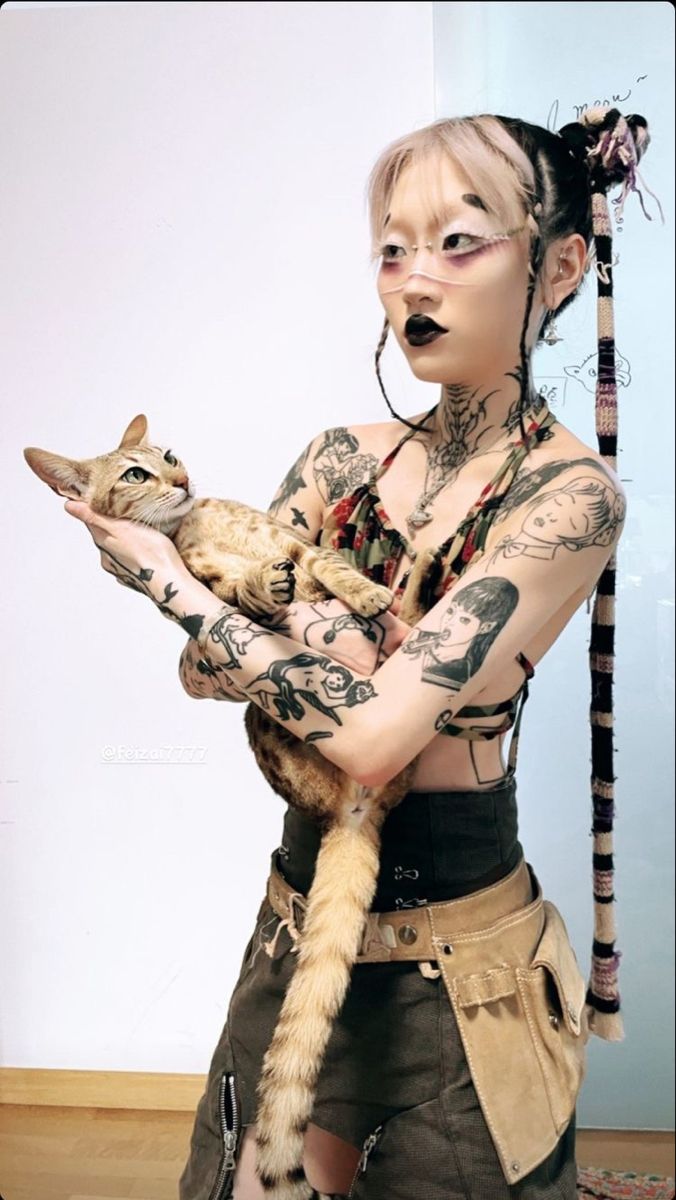 a woman with tattoos holding a cat in her hands