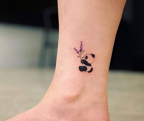 a small tattoo on the ankle of a girl with a panda bear and lavenders