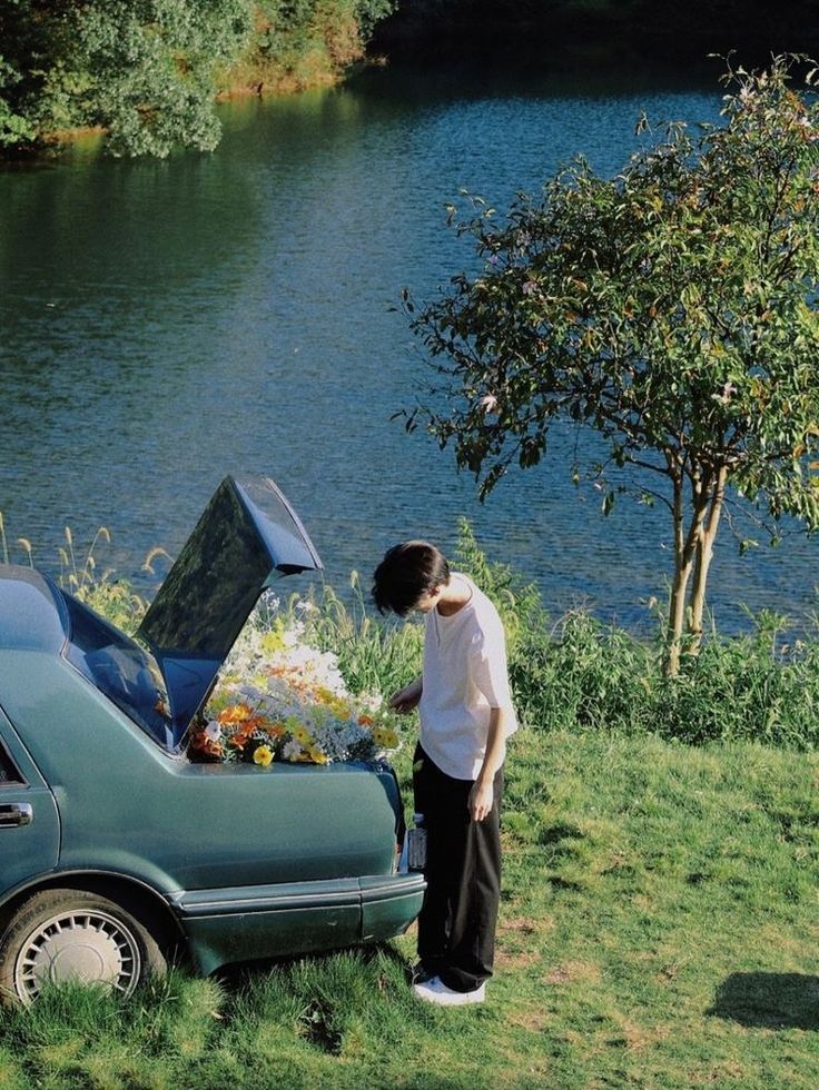 a person standing next to a car with its hood open and flowers in the trunk