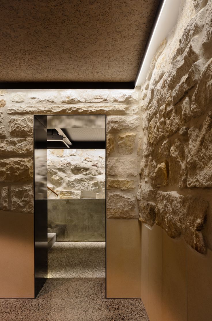 an open door leading to a bathroom with stone walls and flooring on both sides