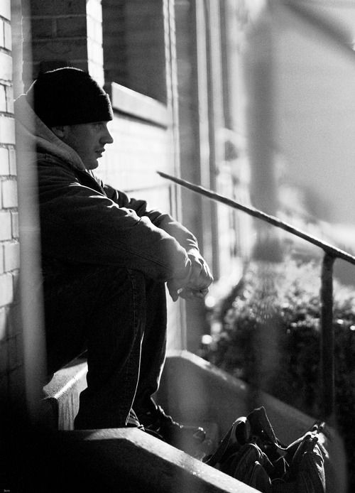 a black and white photo of a man sitting on a bench