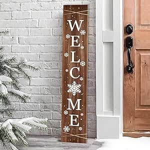 a wooden welcome sign sitting in front of a brick wall next to a snow covered tree