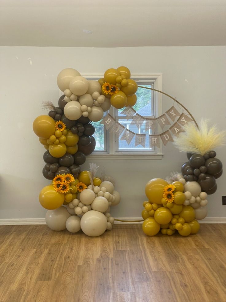 balloons are arranged in the shape of an arch with sunflowers and other flowers