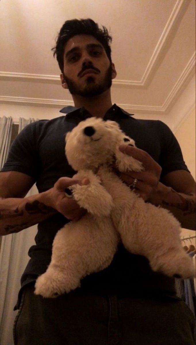 a man holding a white teddy bear in his hands