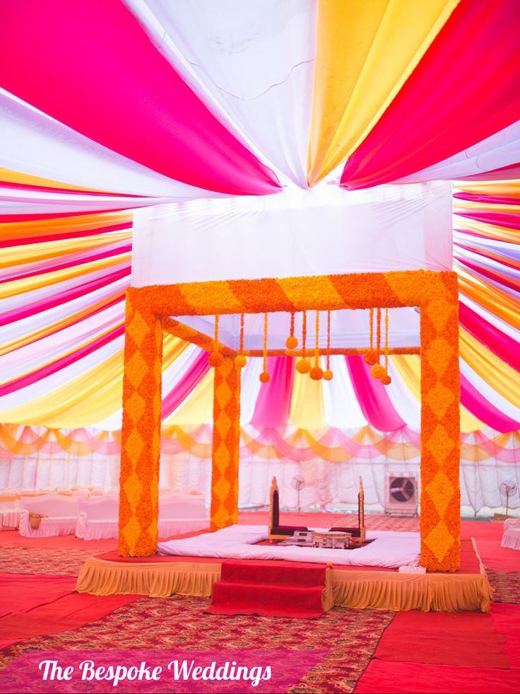 an orange and yellow wedding setup with draping on the ceiling is ready for guests to arrive