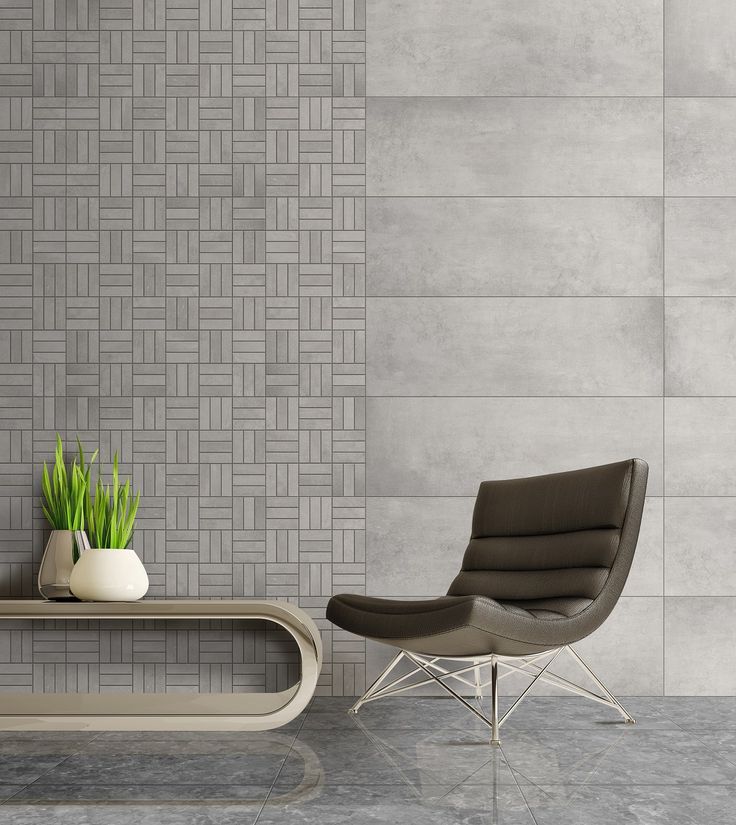 a chair and table in front of a wall with grey tiles on it, next to a potted plant