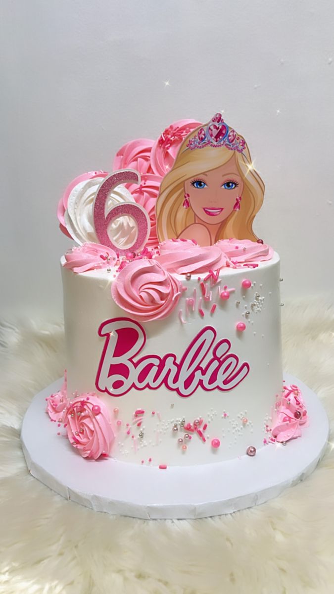 a barbie birthday cake with pink frosting and roses on top, sitting on a white furnishing