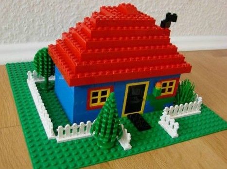 a toy house made out of legos sitting on top of a wooden floor