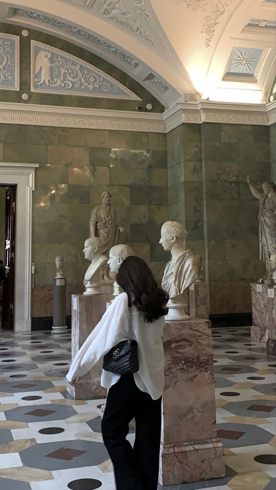 a woman is looking at statues in a room with marble walls and flooring,