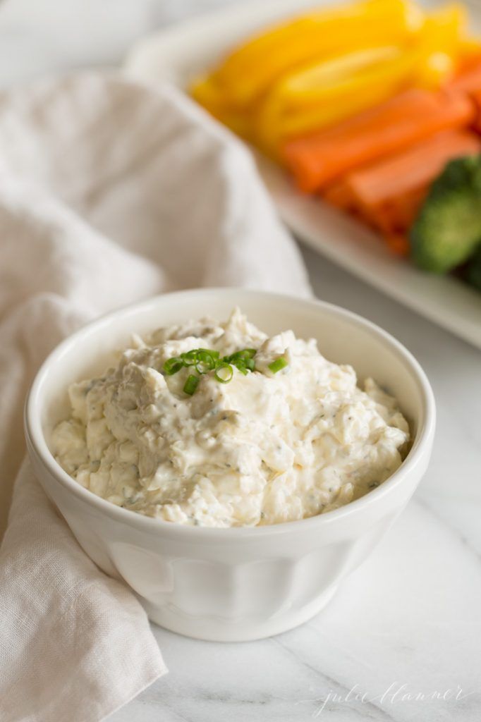 a white bowl filled with mashed potatoes and carrots next to a plate of sliced cucumbers