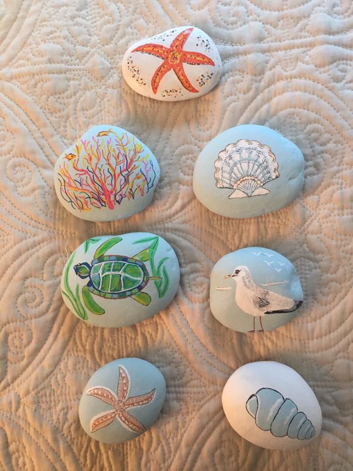 six painted rocks with sea animals and seashells on them sitting on a quilt