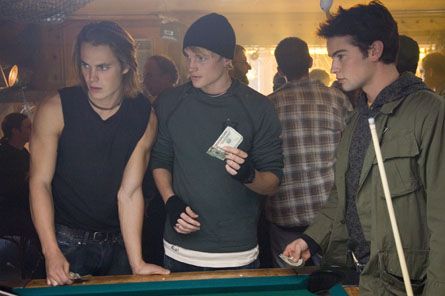 three young men standing around a pool table with one holding a bill and the other looking at something