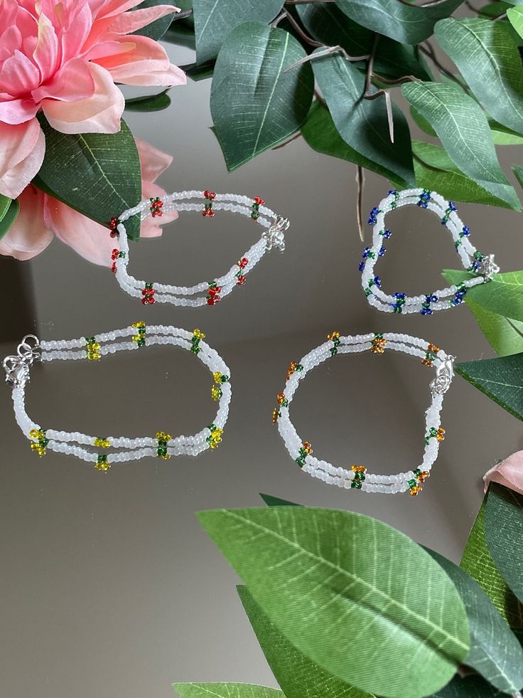 three pieces of jewelry sitting on top of a table next to some leaves and flowers