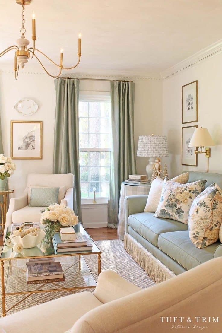 a living room filled with furniture and flowers on the coffee table in front of a window