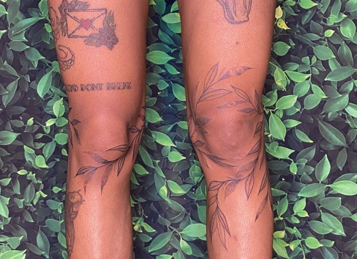 the legs of a woman with tattoos on them are standing in front of green leaves