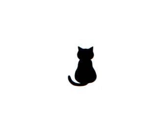 a black cat sitting on top of a white wall