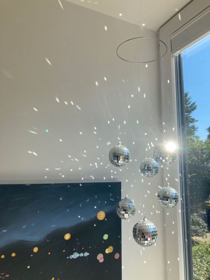 the sun shines brightly in front of a window with disco balls hanging from it