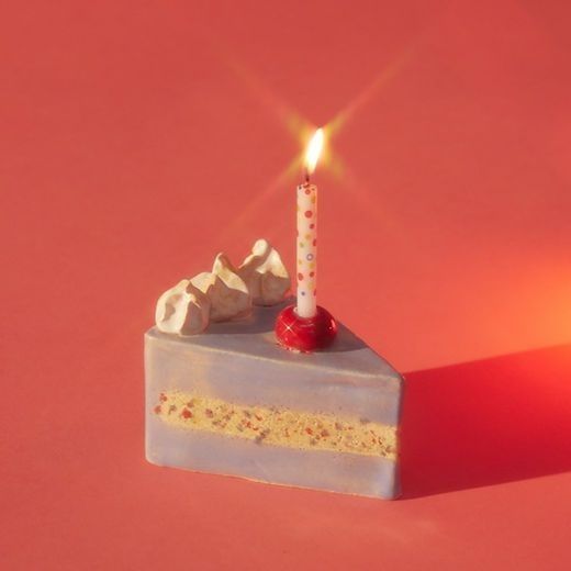 a piece of cake with a single candle on it sitting on a red table top