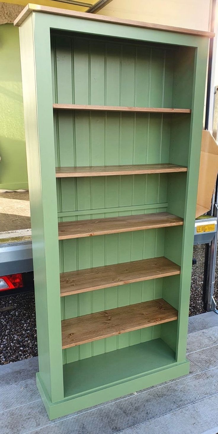 a green bookcase sitting on the side of a road