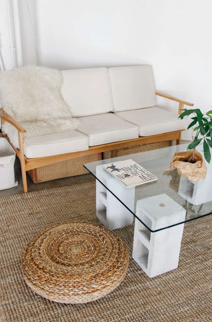 a white couch sitting next to a glass table on top of a rug