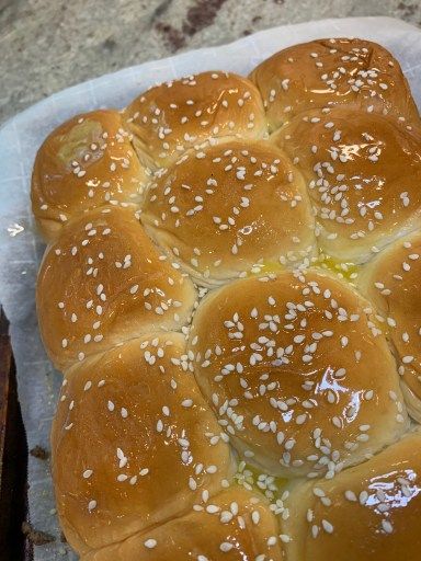 a bun with sesame seeds on it sitting on a piece of wax paper