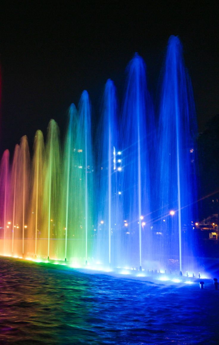 the colorful fountains are lit up at night