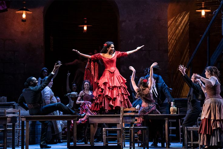 a group of people on stage with one woman in red dress and the other man in black