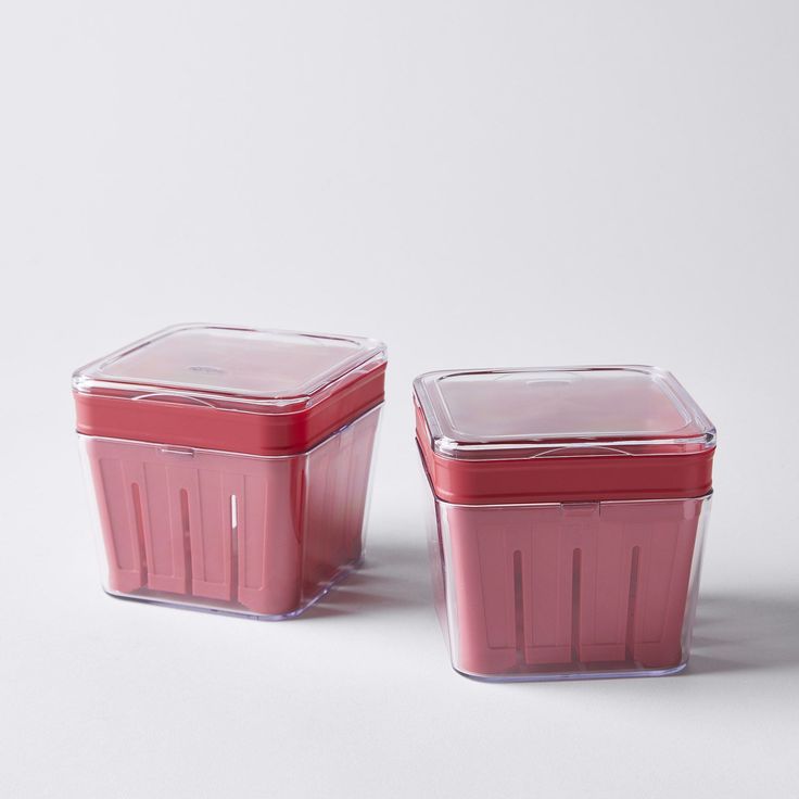 two plastic containers sitting next to each other on a white surface with no one in it