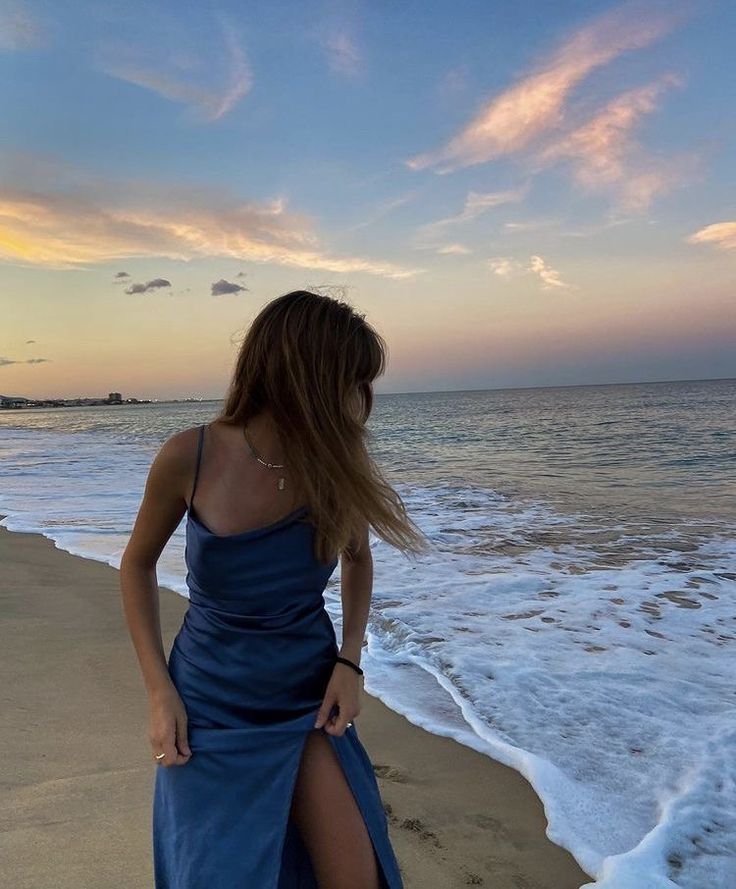 a woman standing on top of a beach next to the ocean