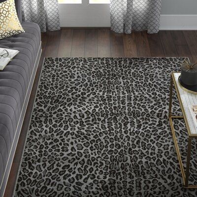 a living room with a gray couch and leopard print rug on the floor next to a window