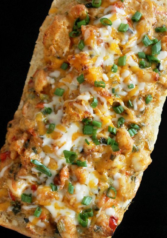 a piece of flat bread with cheese and green onions on it, sitting on a black surface