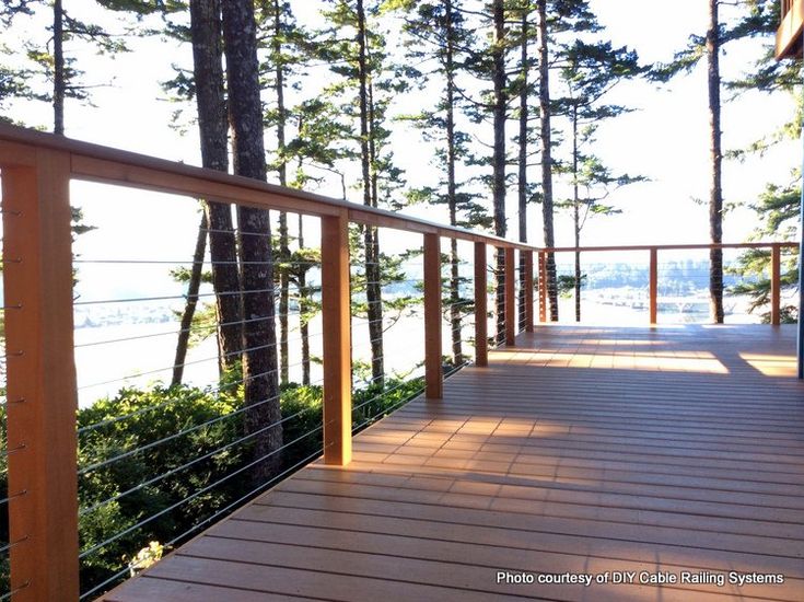 a wooden deck with railing and trees in the background