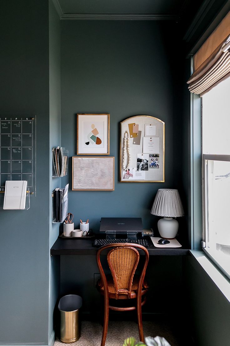 a desk with a chair, lamp and pictures on the wall in a home office