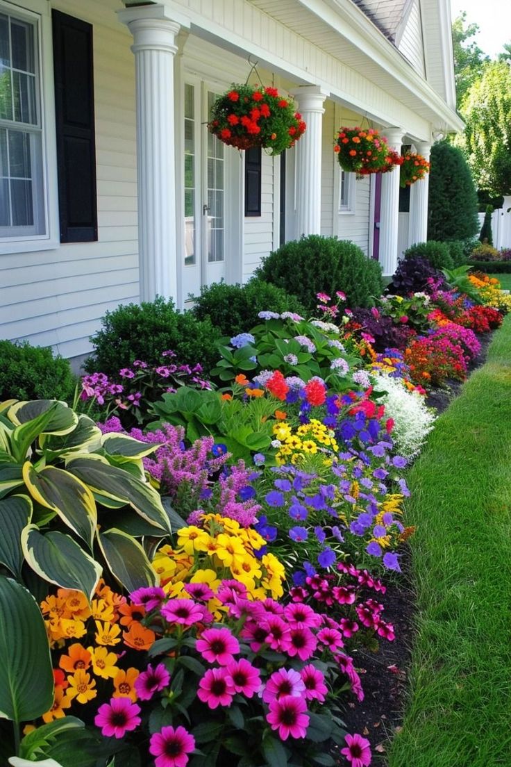 colorful flowers line the side of a white house